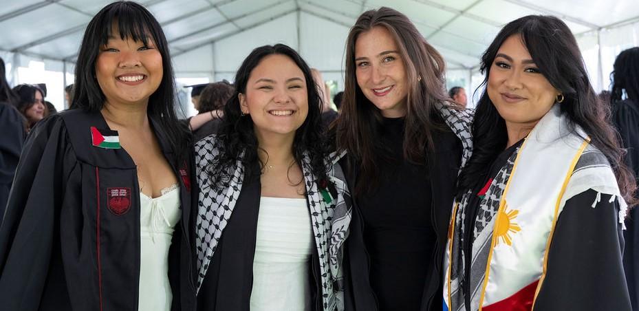 Four graduates in robes smiling