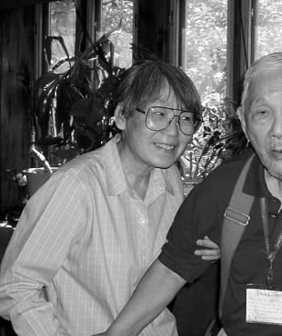 Black and white photo of San Luong assisting an elderly man