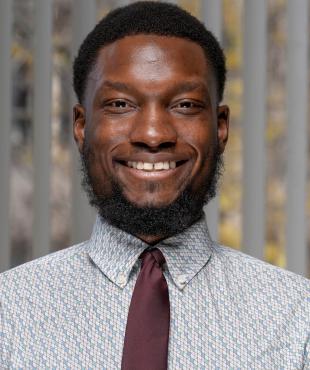 Guy smiling in maroon tie in front of window