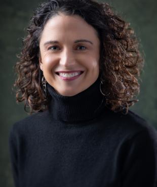 Woman in Black sweater with curly hair smiling 