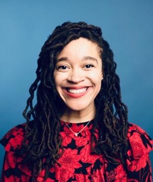 Woman smiling in red and black flower dress in front of a blue background