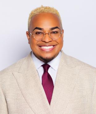 Black man wearing tan suit smiling for headshot