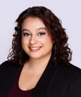 Woman in black with curly hair smiling for headshot