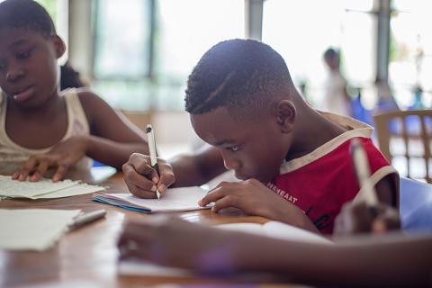 Young student concentrates on writing at desk in classroom