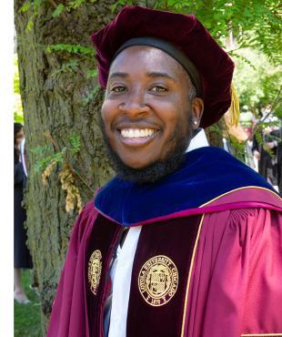 man in a graduation robe with a velvet hood and cap