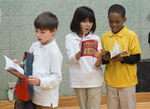 Three elementary students reading books