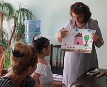A teacher holding up a girl's drawing of her house