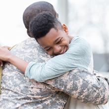 Son hugging father in military uniform 