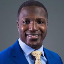 man in blue suit with yellow tie smiling