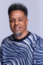 Man in blue in grey sweater smiling with 