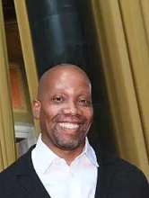 image of man smiling in white shirt no tie with black cardigan