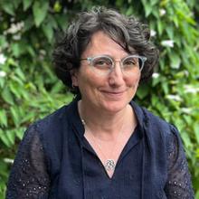 Woman wearing a navy blouse smiling with eyeglasses