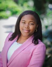 Headshot of Janelle Goodwill in pink jacket with white shirt outdoors