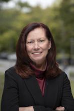 Headshot of Dean Gorman Smith with a maroon blouse and black jacket smiling 