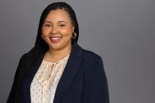 Headshot of Fatima Cooke in blue jacket with light colored shirt smiling