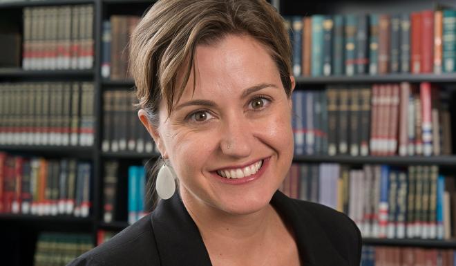 Jennifer Mosley, a female-presenting person, smiles towards the camera in a library.